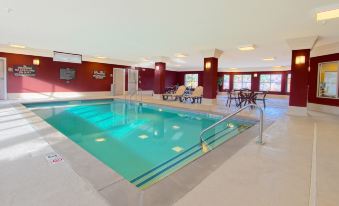 an indoor swimming pool with a diving board , surrounded by red walls and a ceiling at Homewood Suites by Hilton Bloomington