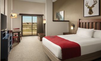 a hotel room with a bed , table , chairs , and a balcony view of the outdoors at Great Wolf Lodge Grapevine