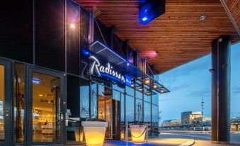 a modern building with a large neon sign above the entrance , welcoming guests to their hotel at Radisson Blu Hotel Uppsala