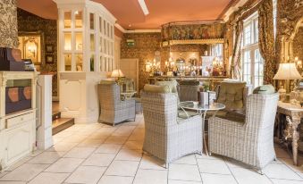 a well - lit room with multiple chairs and tables arranged in a cozy setting , creating a comfortable atmosphere at Coombe Abbey Hotel