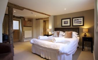 a large bed with white linens is in a room with wooden beams and framed pictures at The Woolpack Inn