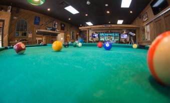a pool hall with a green pool table and several pool balls scattered around the room at Skyline Lodge