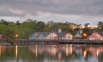 a group of houses situated on the shore of a body of water , with trees and a cloudy sky in the background at Colonial Inn