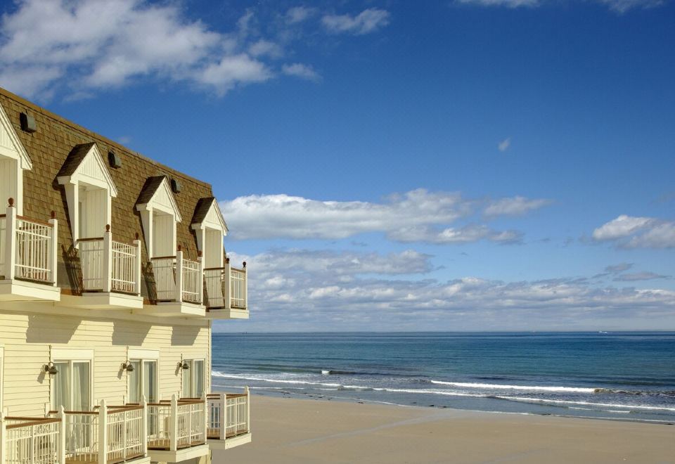 a beach scene with a house on the shore and the ocean in the background at Nantasket Beach Resort