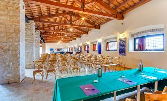 a large dining room with wooden tables and chairs , a green tablecloth , and a red bulletin board at La Tonnara di Bonagia Resort