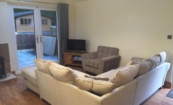 a living room with two beige couches , a gray armchair , and a sliding glass door at Shellow Lane Lodges