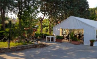 a large white tent is set up in a yard with trees and benches around it at Hotel Miramonti