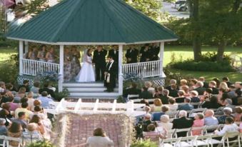 a wedding ceremony taking place in a gazebo , with the bride and groom standing at the front of the stage at Woodbine Inn and Restaurant