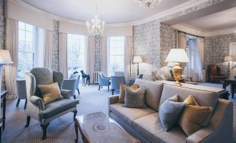 a luxurious living room with blue and white floral wallpaper , elegant furniture , and a chandelier at Rowton Castle