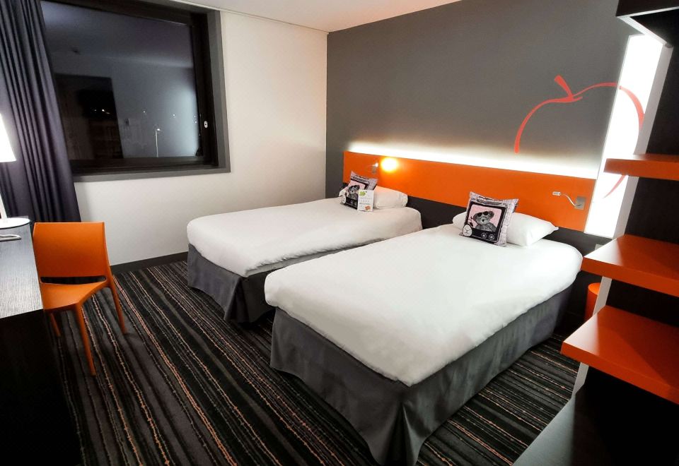 a hotel room with two beds , each made up with white linens and orange headboards at Ibis Styles Caen Centre Gare