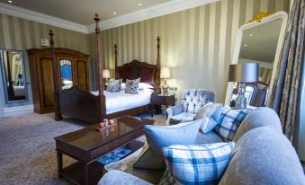 a luxurious hotel room with a large bed , two chairs , and a desk , decorated with blue and white pillows at Bovey Castle