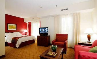a hotel room with a red and white color scheme , featuring a bed , a chair , a tv , and a table at Residence Inn Fort Lauderdale Weston
