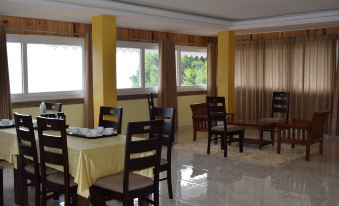 a dining room with a large window , wooden chairs and tables , and yellow curtains on the windows at Sleeping Buddha
