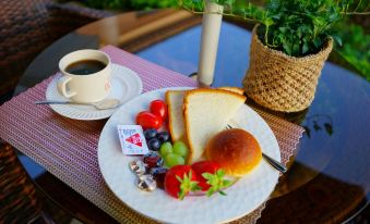 A plate with meat, cheese, and fruit is served alongside coffee or tea at Jeonju Dwaejikkum Hanok