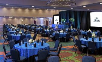 a large conference room filled with blue tables and chairs , ready for an event or meeting at Hilton Lexington/Downtown