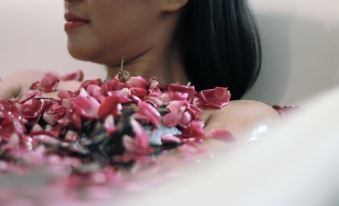 a woman is sitting in a bathtub filled with pink flowers , enjoying a bubble bath at Tjokro Hotel Klaten
