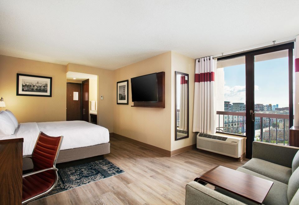 a hotel room with a bed , couch , and tv , along with a view of the city through a window at Four Points by Sheraton - San Francisco Bay Bridge