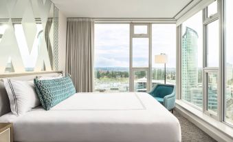 a large bed with white sheets and a blue pillow is in a room with a window at Civic Hotel, Autograph Collection