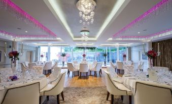 a large dining room with white tablecloths , multiple chairs , and a chandelier hanging from the ceiling at Galgorm