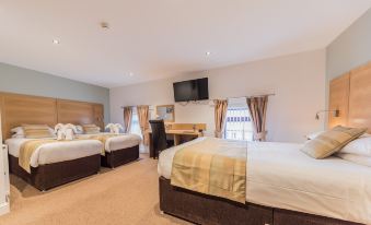 a large hotel room with three beds , two of which are double beds and one is a single bed at The Old Ginn House Inn