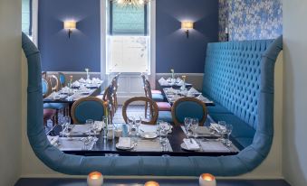 a dining room with blue and white walls , a long table set for a formal dinner , and multiple chairs arranged around it at The Celtic Royal Hotel