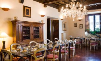 a dining room with wooden chairs and tables , a chandelier hanging from the ceiling , and framed pictures on the wall at Villa Campestri Olive Oil Resort