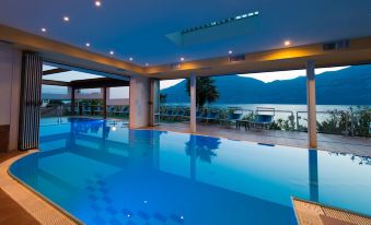 a large , rectangular swimming pool with blue water and white tiles , surrounded by a balcony with a view of the sea at Hotel Eden