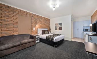 a modern hotel room with a brick wall , a bed , and a couch , along with a door leading to another room at Peppermill Inn Motel