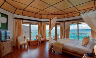 a luxurious bedroom with a large bed , wooden furniture , and a view of the ocean at Angaga Island Resort & Spa