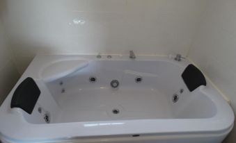 a white bathtub with jets and handles , located in a bathroom with white walls and gray floor at Brooklyn Motel