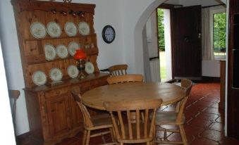 a dining room with a wooden dining table and chairs , a cabinet filled with plates , and a red tiled floor at Greenhollow