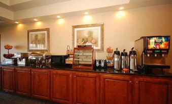 a dining area with a buffet table filled with various food items and beverages , including coffee makers , sandwiches , and other snacks at Franklin Inn and Suites