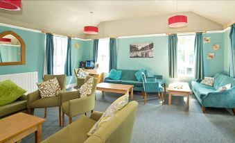 a brightly lit room with blue walls , green furniture , and red pendant lights , creating a cozy atmosphere at YHA Malham