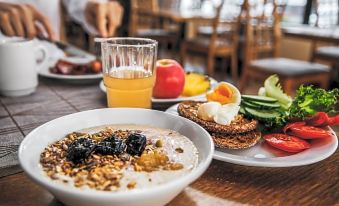 a dining table with a variety of food items , including a bowl of cereal , a plate of eggs , and a glass of juice at Hotel Savoy