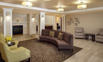 a modern living room with a curved brown couch , marble fireplace , and beige walls , decorated with recessed lighting at Homewood Suites by Hilton Wallingford-Meriden