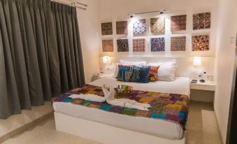 a white bedroom with a bed , two lamps , and a quilt on top of it at Mayas