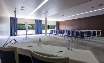a conference room with blue chairs and tables , water bottles on the table , and a whiteboard at Douro Palace Hotel Resort & Spa
