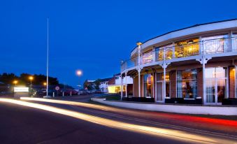 a city street at night , with a building on the left side and a car driving down the road at Langstone Quays Resort