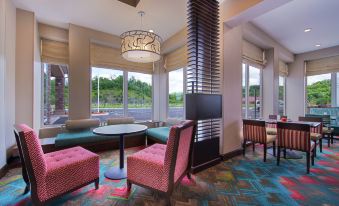 a modern , well - lit room with large windows and pink furniture , including two chairs and a couch at Hilton Garden Inn Bristol