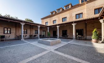a courtyard with a fountain surrounded by buildings , creating a serene and picturesque atmosphere at Castilla Termal Olmedo