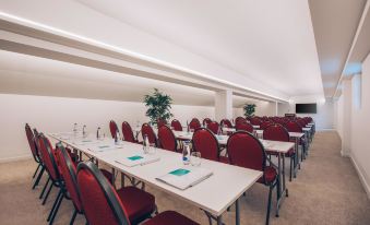 a large conference room with rows of red chairs arranged in a semicircle , and several tables with green placemats at Heritage Grand Perast by Rixos