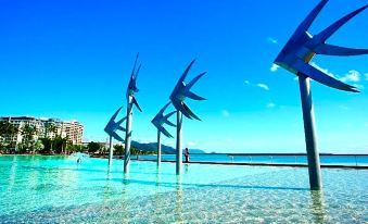 a sculpture of three birds on the water , with a city in the background and a person standing in the foreground at Cairns Sunland Leisure Park