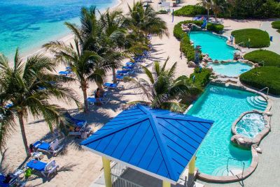 a resort with a pool and a beach , surrounded by palm trees and a blue gazebo at Wyndham Reef Resort Grand Cayman