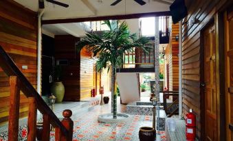 a spacious living room with wooden walls , a large potted plant , and a staircase leading to the second floor at Kampong Pinang Sebatang