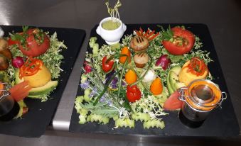 a plate of fresh vegetables and fruit is displayed on a table with a small bowl of sauce at Le Continental