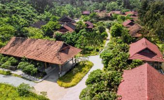 a bird 's eye view of a resort with red - roofed buildings and lush greenery surrounding a winding path at Quynh Vien Resort Ha Tinh