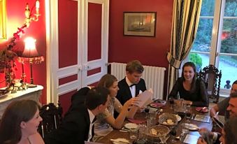 a group of people gathered around a long dining table in a room , enjoying a meal together at Chateau de Beaulieu