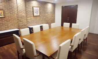 a large wooden conference table surrounded by white chairs in a room with brick walls at Kautaman Hotel