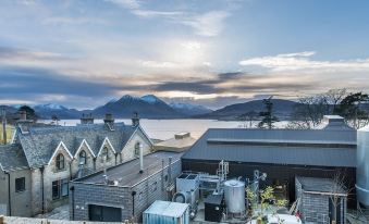a rooftop with a view of the mountains and water , as well as several buildings in the background at Isle of Raasay Distillery