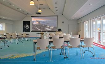 a large conference room with multiple rows of chairs arranged in front of a projector screen at Hotel Arctic